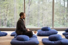 Man sitting on meditation pilliows.